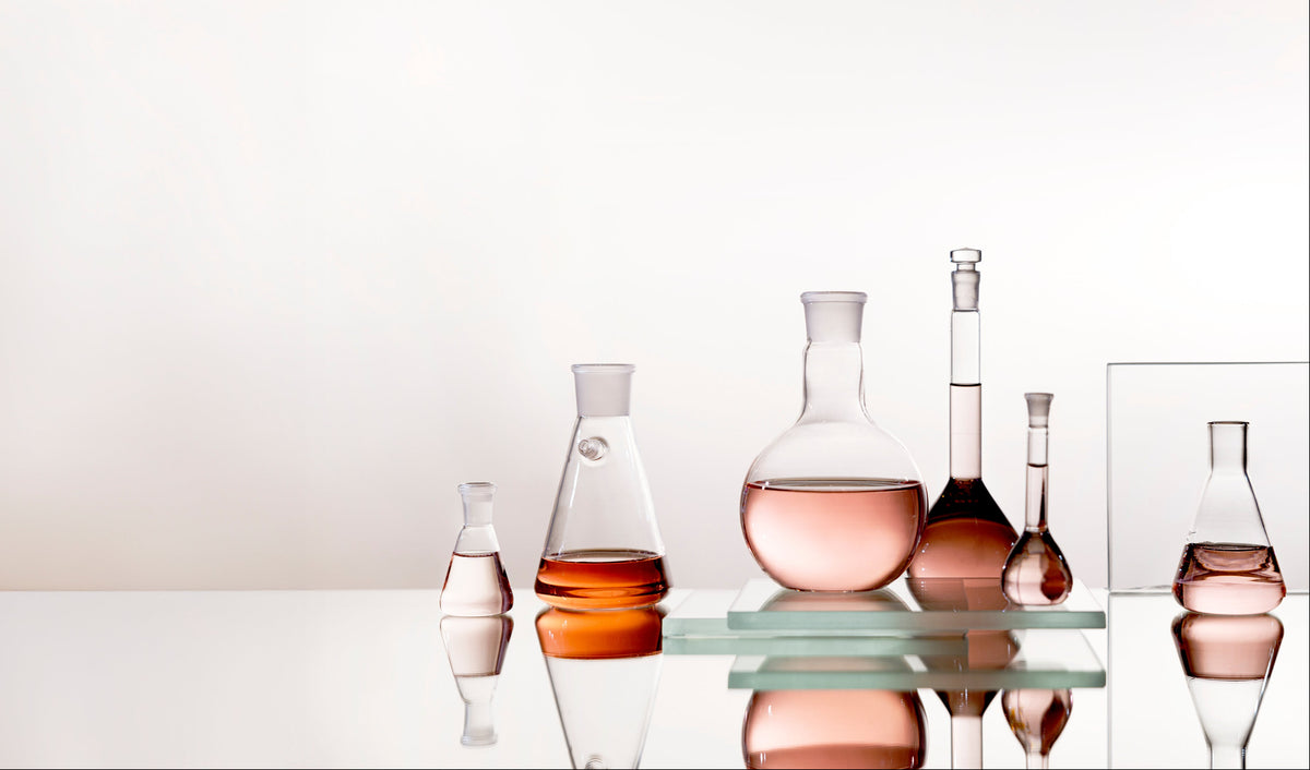Set of glass bottles with different shapes and colors on a reflective surface.